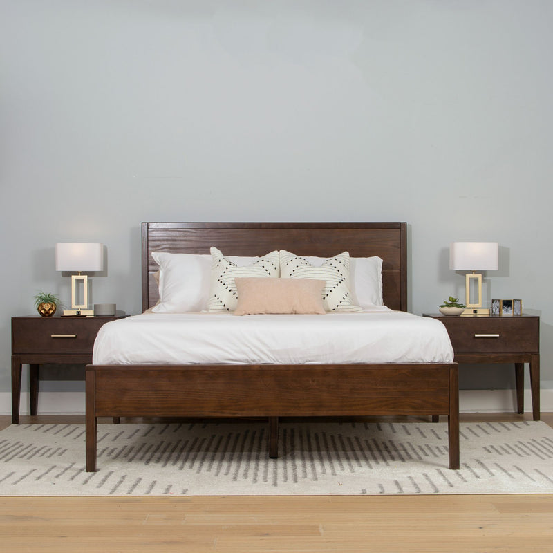 Modern wooden bed frame with white bedding and accent pillows in a minimalist bedroom setting, featuring matching nightstands and lamps.