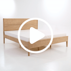 Modern minimalist light oak platform bed frame with paneled headboard and white mattress on a white studio background