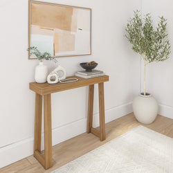 Minimalist entryway with wooden console table, neutral ceramic vases, abstract framed artwork, decorative bowl on books and potted olive tree — modern Scandinavian home decor