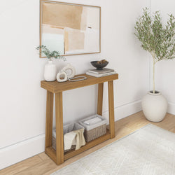 Minimalist entryway console table with abstract framed art, ceramic vases, black bowl, woven storage baskets and potted olive tree