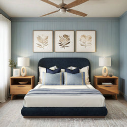 Elegant modern bedroom with navy upholstered bed, stylish lamps, wooden nightstands, and botanical artwork on blue paneled walls.