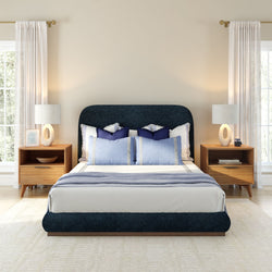 Modern bedroom with navy upholstered bed, wooden nightstands, and soft lighting.