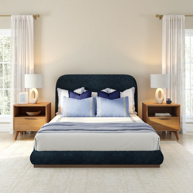 Modern bedroom with navy upholstered bed, wooden nightstands, and soft lighting.