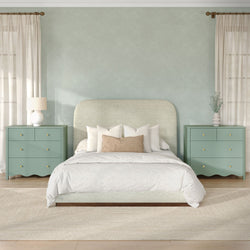 Modern calming bedroom with sage upholstered headboard, matching mint-green nightstands, white bedding, woven accent pillow, table lamps, sheer curtains and potted eucalyptus.