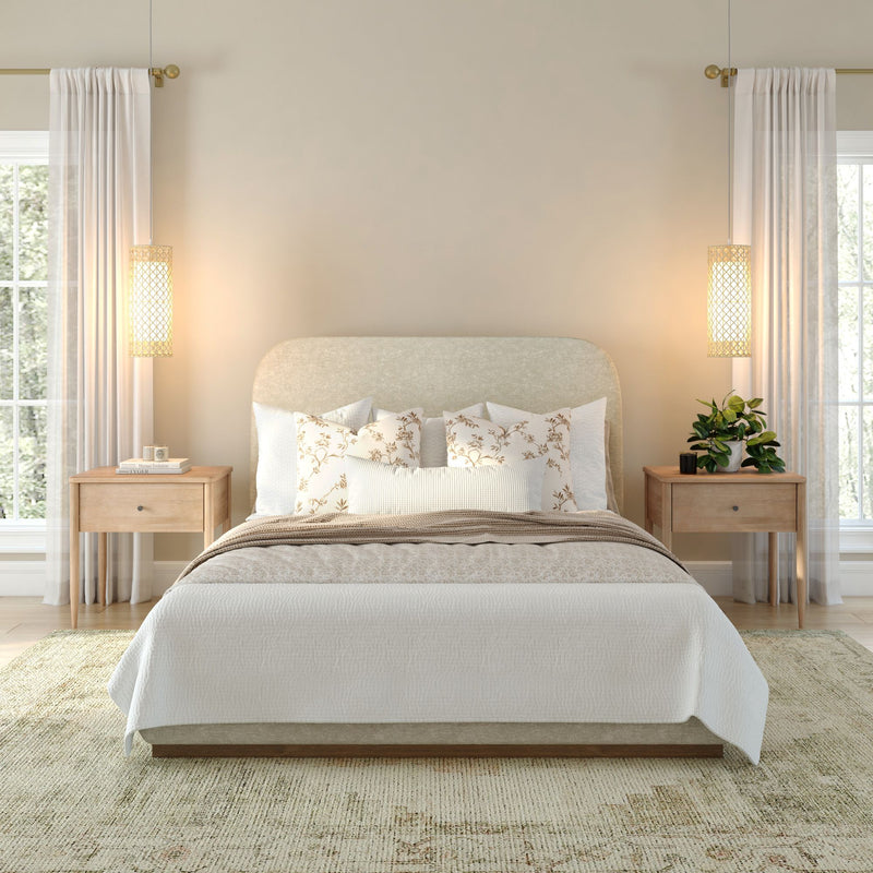 Neutral modern bedroom with beige upholstered headboard, floral pillows, wooden nightstands, pendant lights and sheer curtains