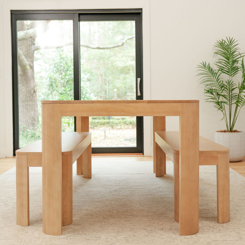 Minimalist wooden dining table set with bench seating in a modern living room.