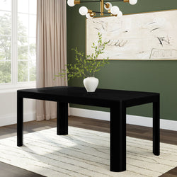 Modern dining room with black table, white vase, and minimalist decor against green accent wall.