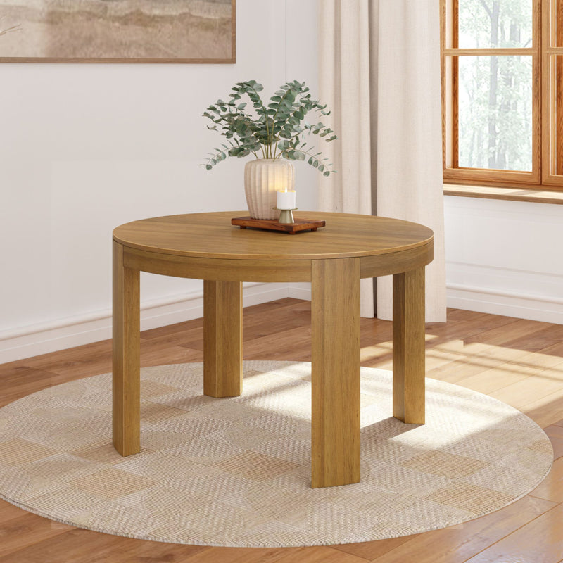 Round wooden dining table with decorative plant and candle in a modern living room setting.