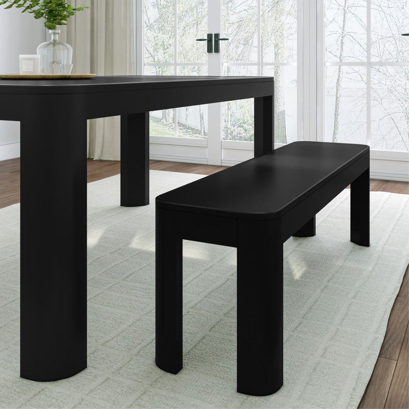 Modern black dining table and bench set in a bright room with large windows.
