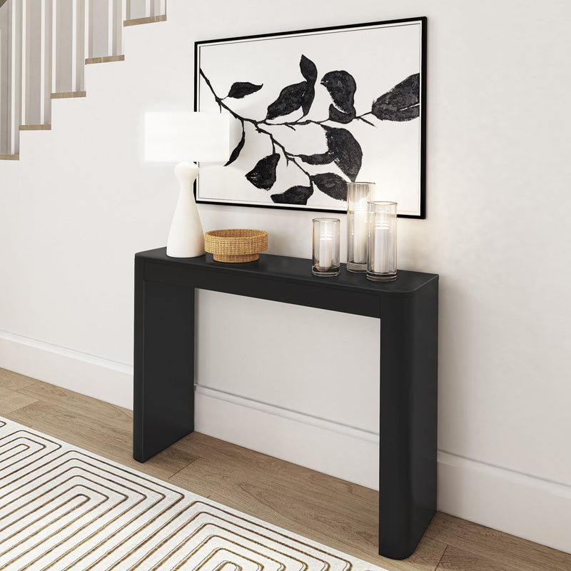 Modern black console table with decorative candles, minimalist lamp, wicker basket, and abstract wall art in a stylish hallway.