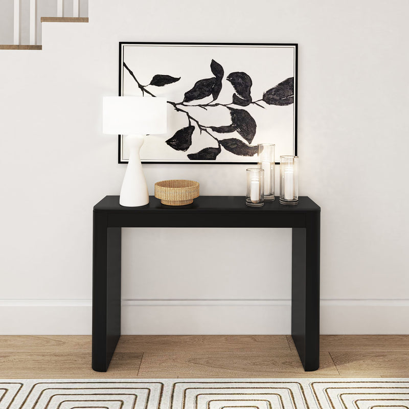 Stylish black console table with decorative items and modern black and white artwork on the wall.