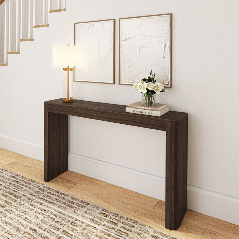 Modern dark wood console table in hallway with decorative lamp, art pieces, and flower vase.