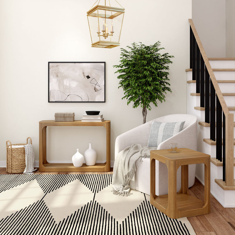 Modern living room interior design with stylish furniture, geometric rug, and potted plant near staircase.