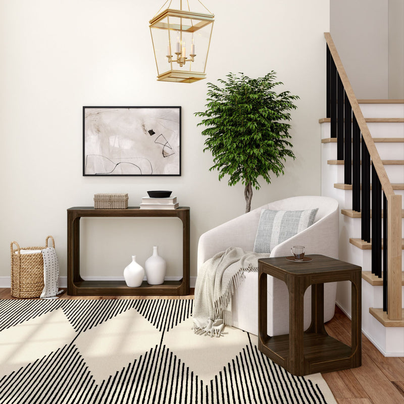 Elegant modern living room with white armchair, geometric rug, and decorative plant by staircase.