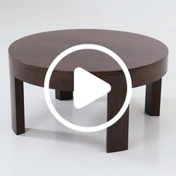 Dark brown round wooden coffee table with four square legs, modern low-profile living room table on white studio background