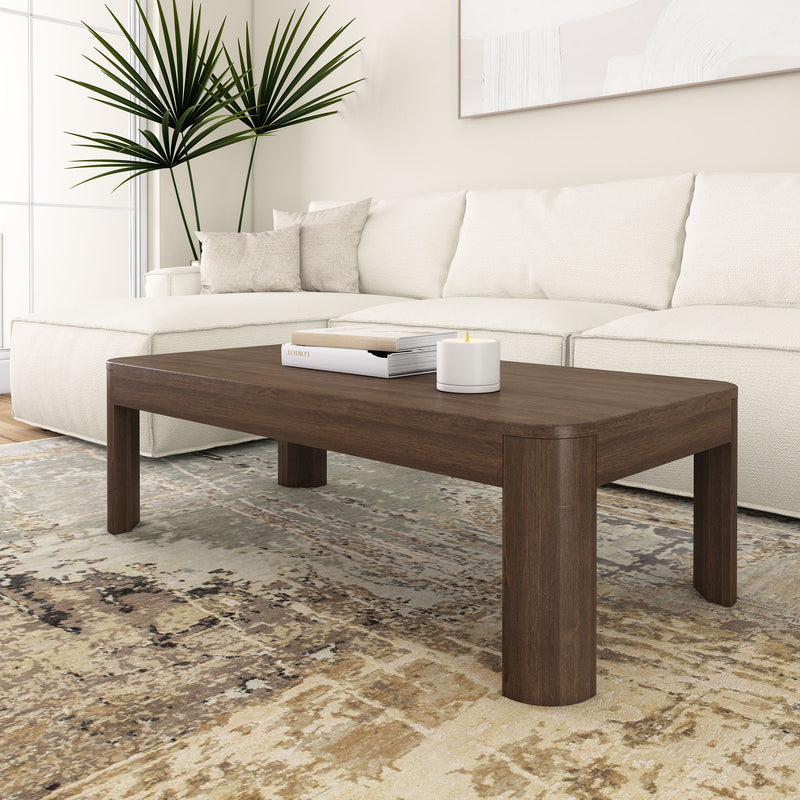 Modern living room with a sleek wooden coffee table, white sofa, decorative plant, and contemporary decor.