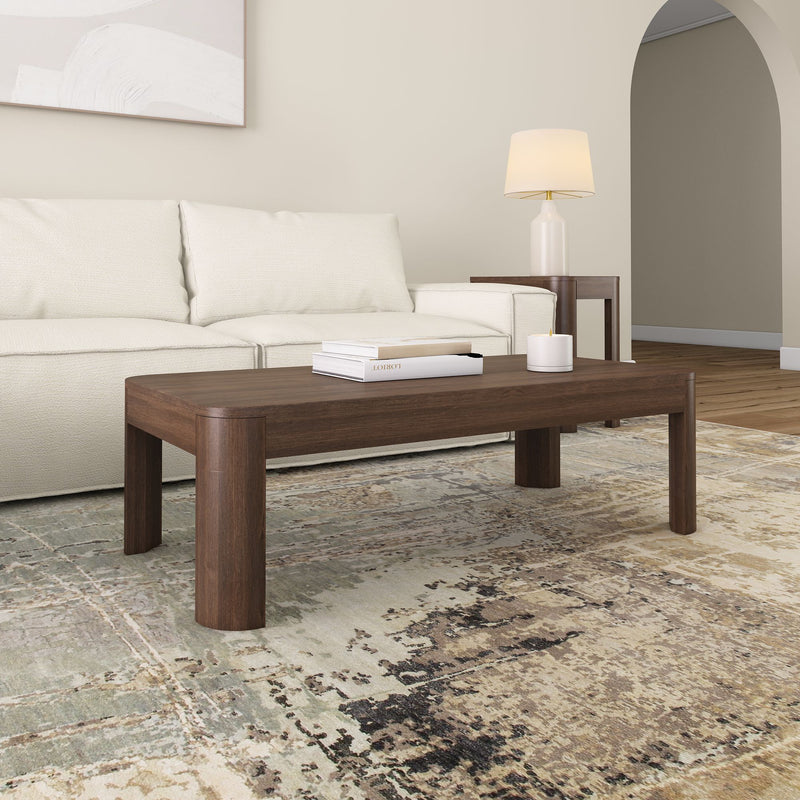 Modern living room with a wooden coffee table, white sofa, and decorative lamp on a patterned rug.