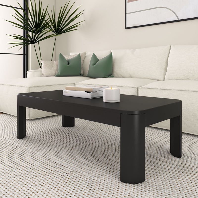 Modern black coffee table in a contemporary living room with white sofa and green accent pillows.