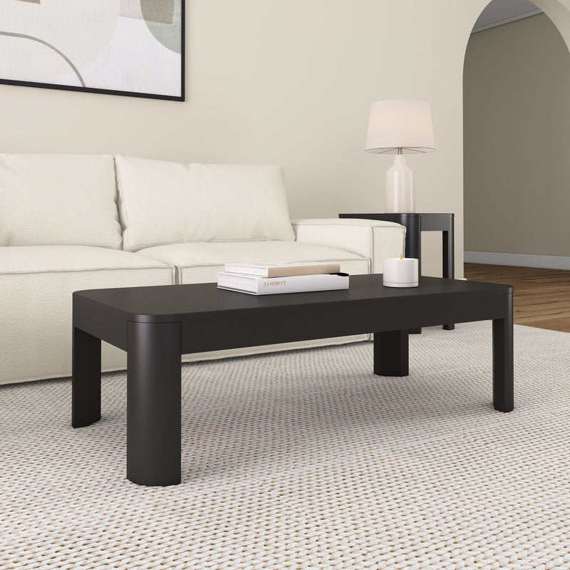 Black modern coffee table in a stylish living room with beige sofa and decorative lamp.