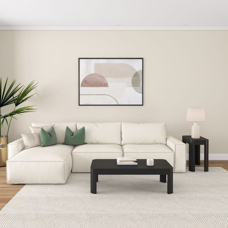 Modern living room with a white sectional sofa, green pillows, abstract wall art, and black coffee table.