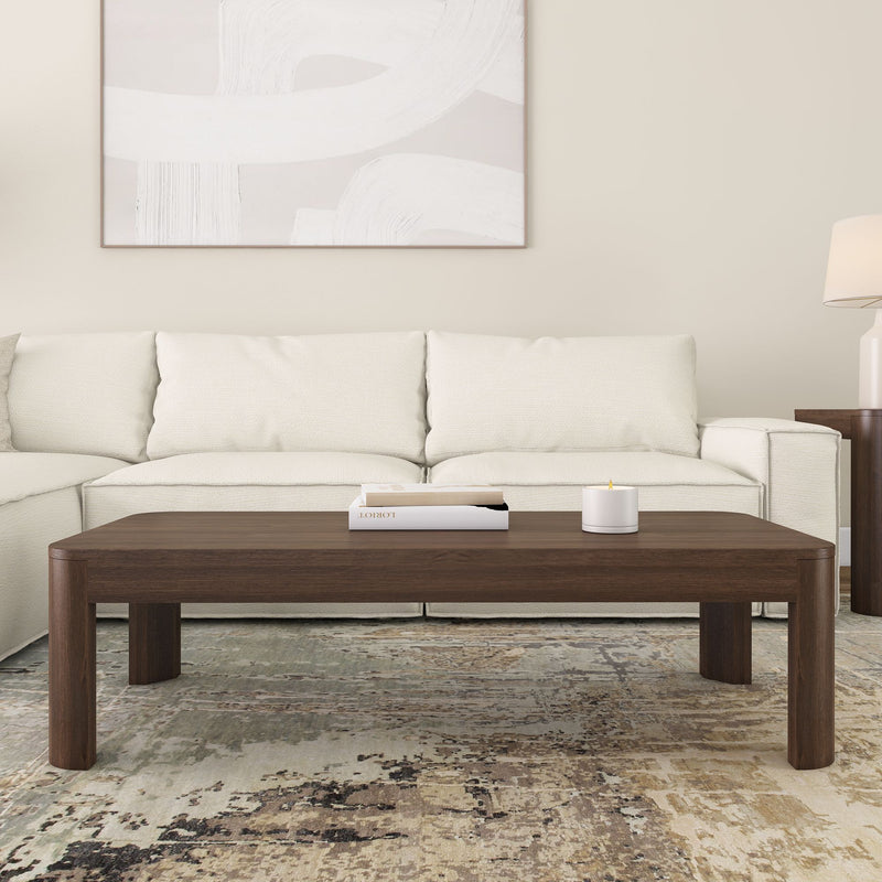 Modern living room with white sofa, abstract artwork, dark wooden coffee table, and contemporary decor accents.