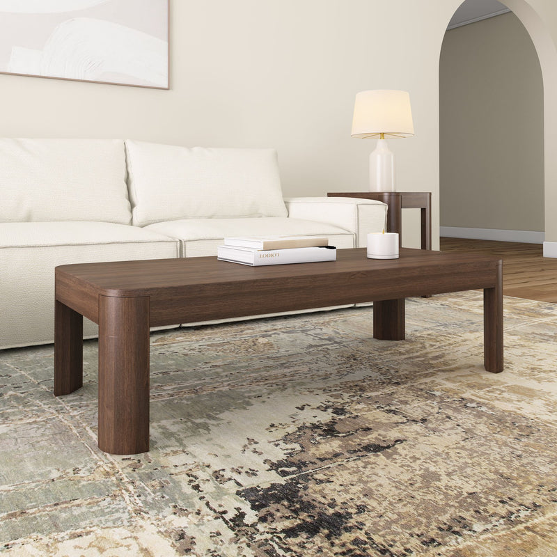 Contemporary living room with a modern wooden coffee table, cream sofa, elegant lamp, and artistic rug.