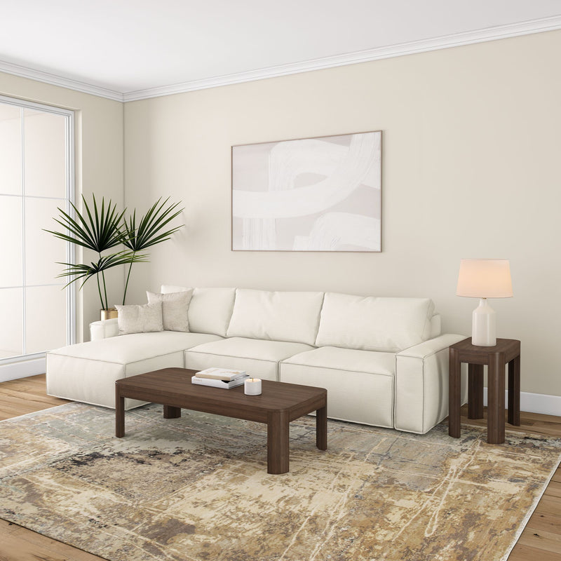 Modern living room with a white sectional sofa, dark wood coffee table, abstract wall art, and potted plant.