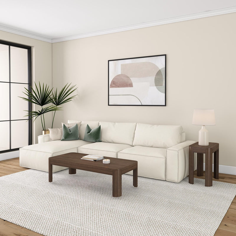 Contemporary living room with beige sectional sofa, wooden coffee table, abstract wall art, and indoor plant.