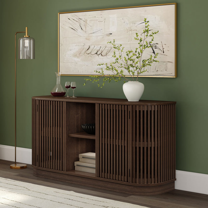 Dark wood slatted sideboard with white vase of greenery, abstract art and gold lamp on green accent wall in living room.