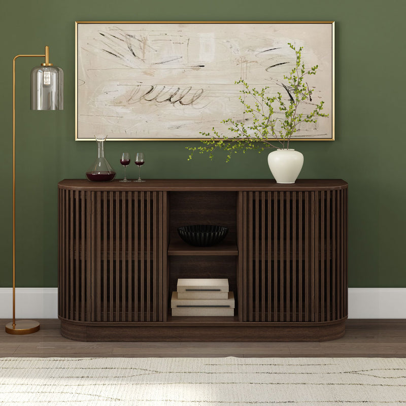 Modern dark wood slatted console table on green accent wall with abstract framed art, white vase with branches, wine decanter and gold floor lamp, contemporary living room decor
