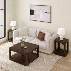 Modern living room with white sofa, dark wood coffee table, matching side tables, abstract wall art, and cozy decor.