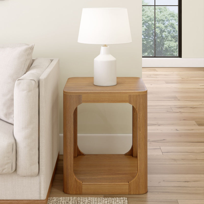 Contemporary wooden side table with a white ceramic lamp next to a beige sofa in a modern living room.