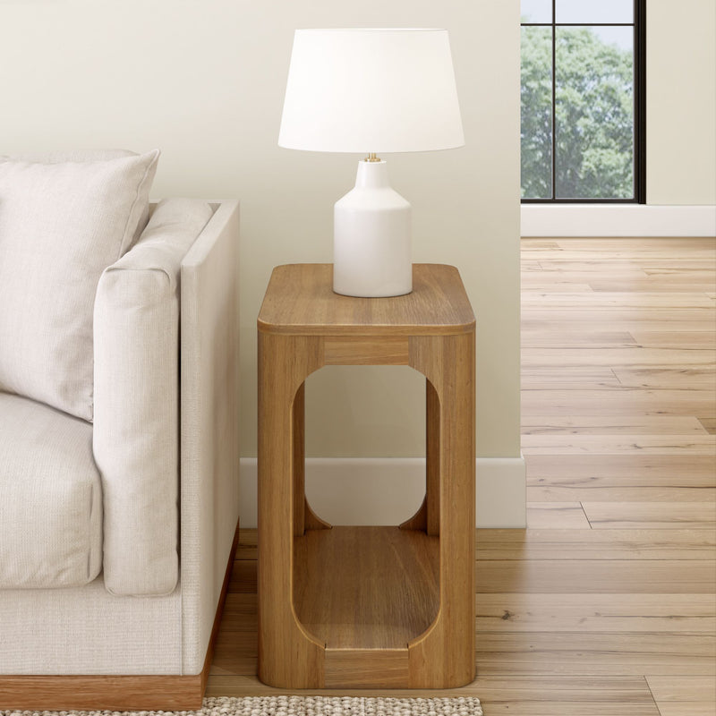 Modern wooden side table with white lamp next to a beige sofa in a living room.