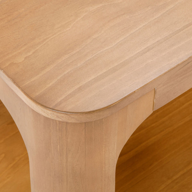 Close-up view of a minimalist wooden table with rounded edges, showcasing a smooth natural finish.