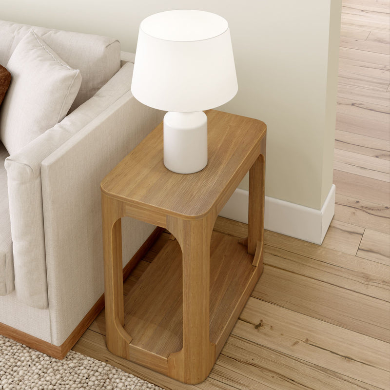 Wooden side table with white lamp next to a beige sofa in a cozy living room setting.