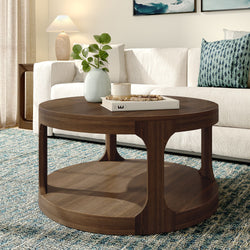 Round walnut coffee table in modern living room with white sectional sofa, blue patterned rug, ceramic vase with green leaves, decorative book and candle