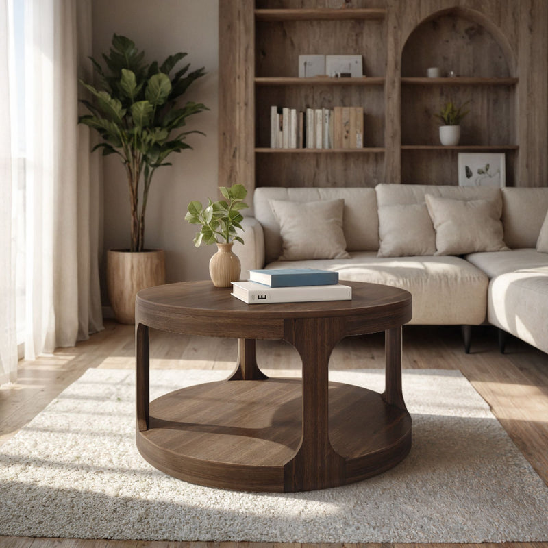 Round dark wood coffee table with books and small vase on rug in a sunlit modern neutral living room with beige sectional sofa, potted plant, and wooden bookshelf