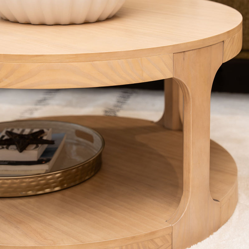 Close-up of a round light oak two-tier coffee table with lower shelf and brass decorative tray in a modern living room