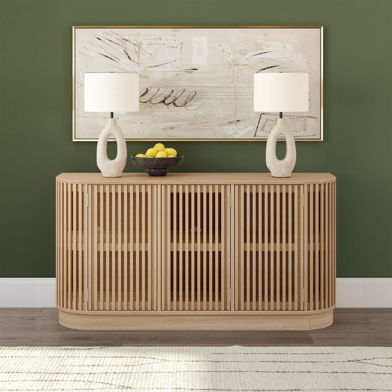 Modern wooden sideboard with slatted design, styled with white lamps and a bowl of lemons against a green wall.