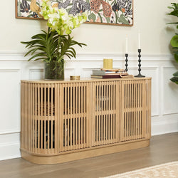 Modern wooden sideboard with vertical slats, decorated with potted plant, candles, and books, in a stylish living room.