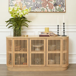 Modern wooden sideboard with plants and candleholders in a stylish living room setting.