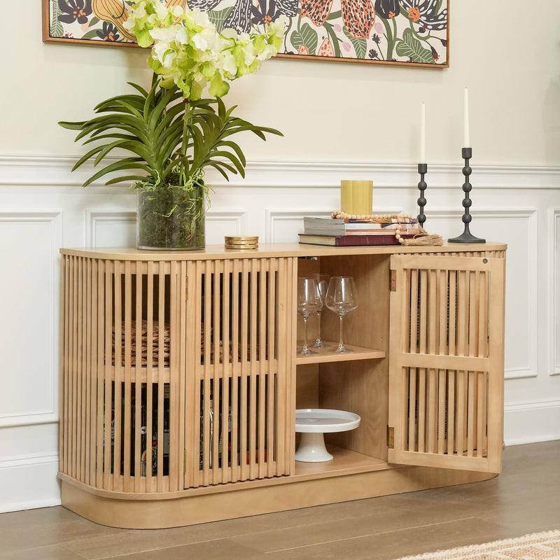 Modern wooden sideboard with open shelving, decorative plants, books, and candles in a stylish living room setting.