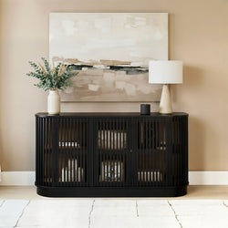 Black slatted console cabinet with rounded corners under beige abstract painting, ceramic table lamp and eucalyptus vase — modern entryway living room decor