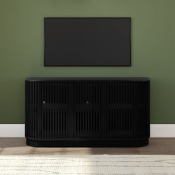 Modern black slatted media console with wall-mounted flat-screen TV on sage green wall, hardwood floor and neutral area rug, minimalist entertainment center