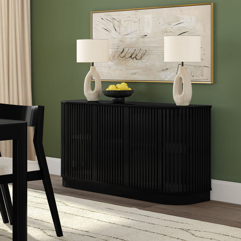 Modern dining room with black slatted sideboard on a green accent wall, sculptural ceramic table lamps, bowl of lemons, and gold-framed abstract art.