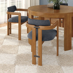 Modern round oak dining table with mid-century wooden chairs featuring gray upholstered seats and vase centerpiece on a neutral textured rug