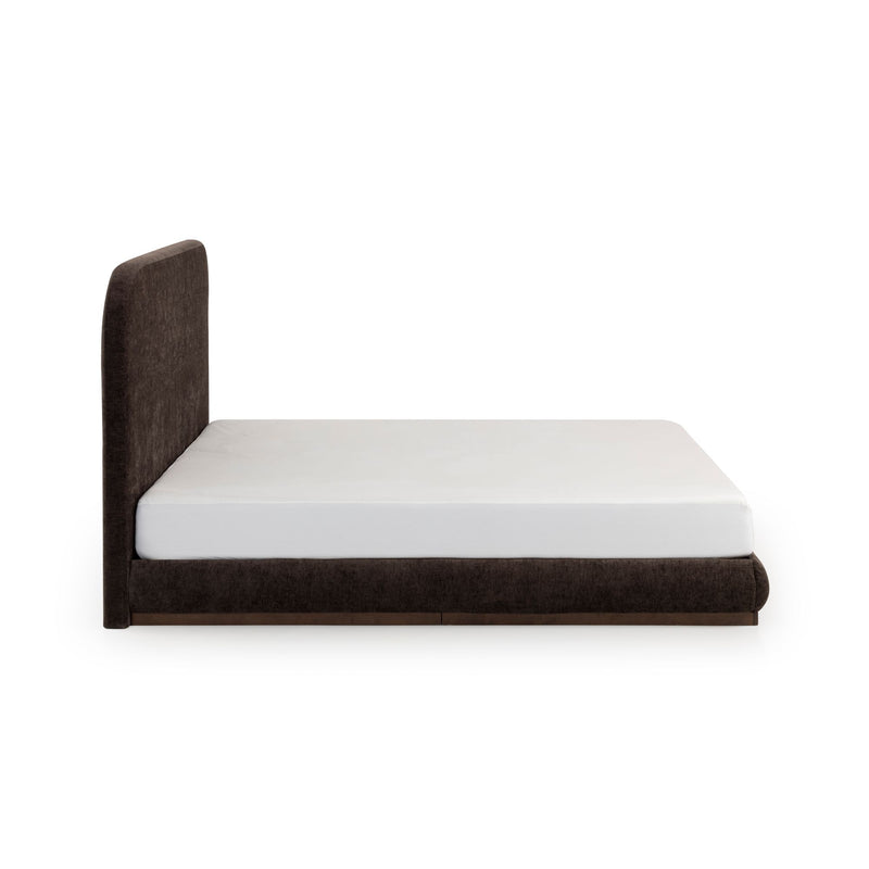 Side view of modern low-profile brown upholstered platform bed with tall rounded headboard and white mattress on white background