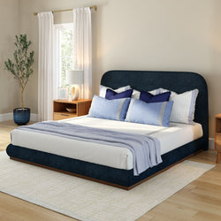 Elegant modern bedroom with navy blue bed frame, stylish throw pillows, and wooden nightstands.