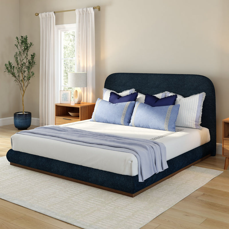 Elegant modern bedroom with navy blue bed frame, stylish throw pillows, and wooden nightstands.