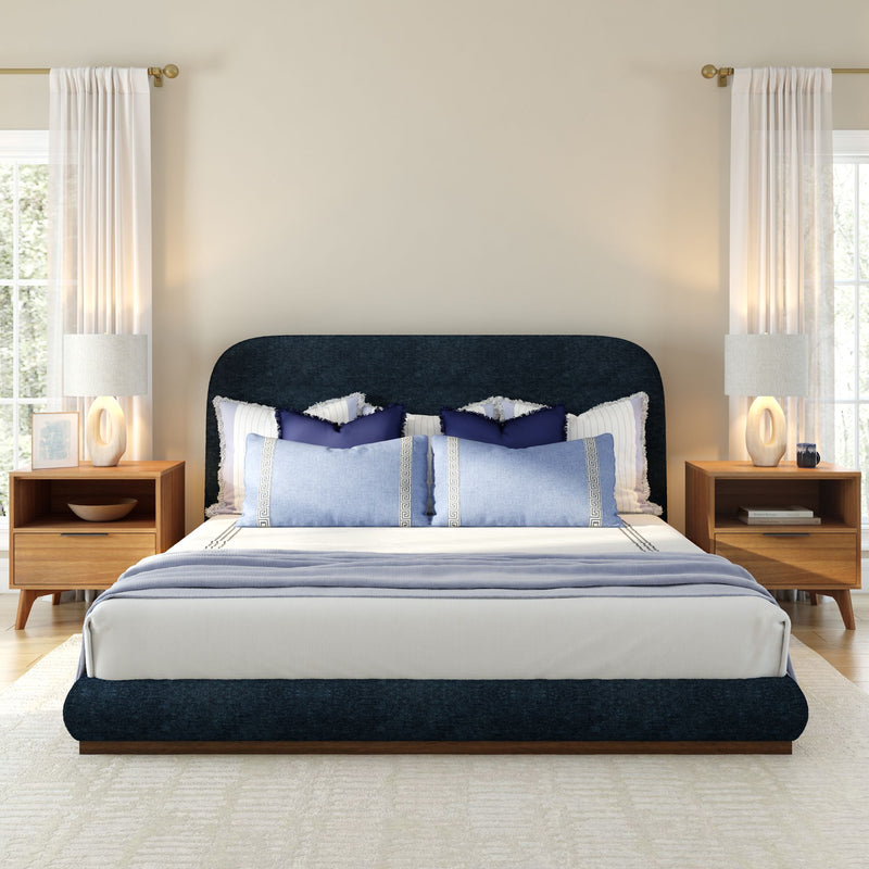 Modern bedroom interior with a stylish navy blue bed, wooden nightstands, and white curtains.